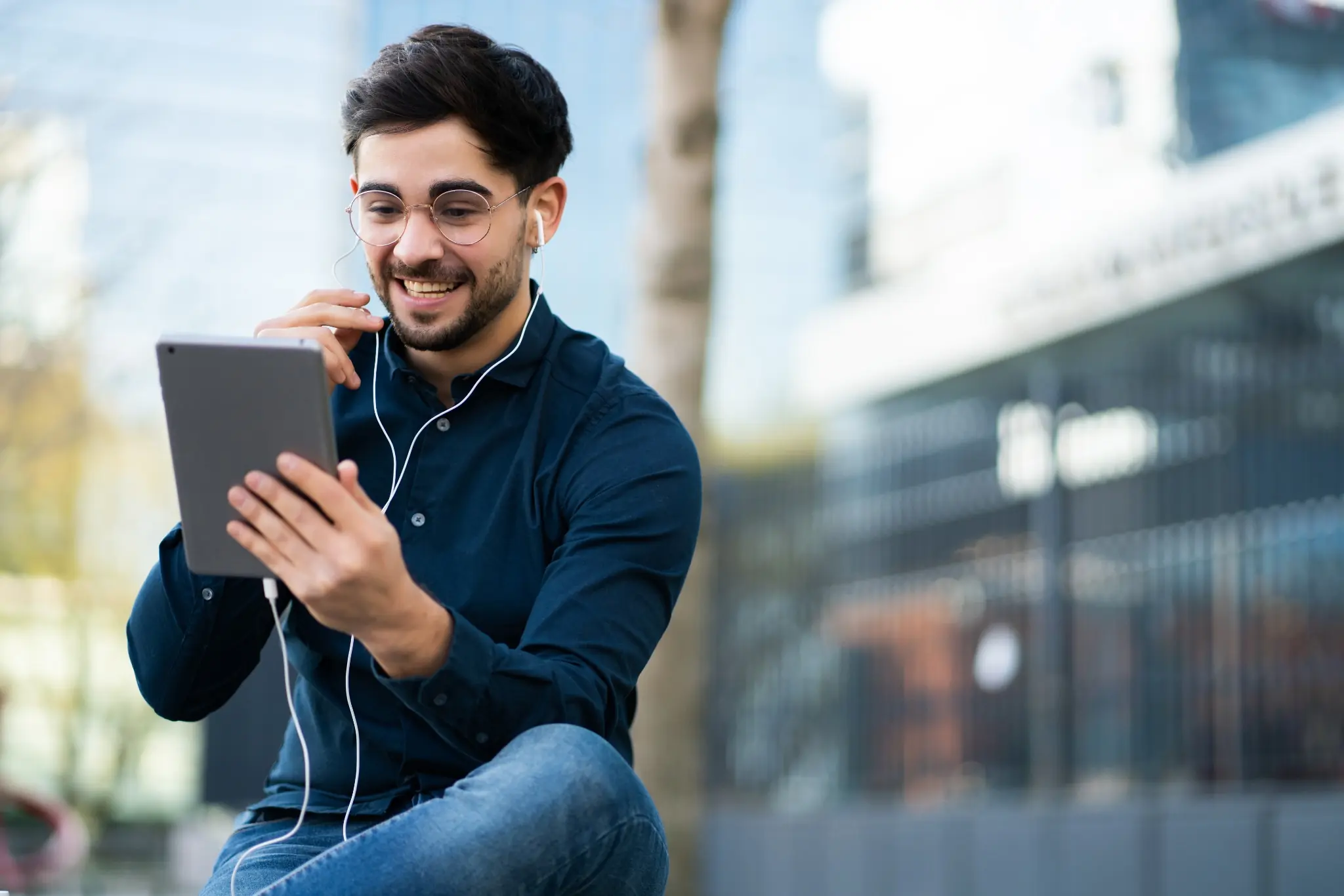 Young man having a video call on digital tablet outdoors.
